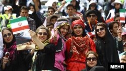 Iran – Women with Iranian flags in Tehran Azadi stadium in a ceremony for honoring the organizers that facilitated cultural activities and travel inside Iran during the two-week Norouz holidays, Tehran, Apr2013 