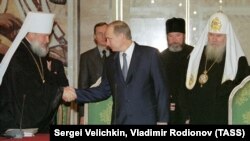 Президент Росії Володимир Путін (посередині), тодішній митрополит Смоленський і Калінінградський Кирило (ліворуч) і Московський патріарх Алексій II. Москва, 13 грудня 2001 року