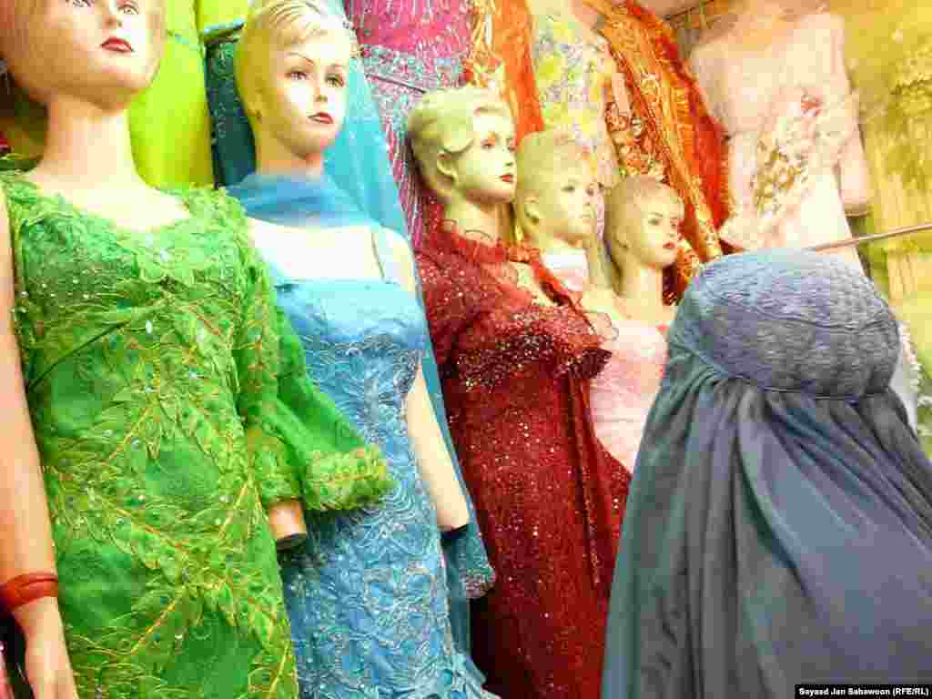 A woman in a burqa examines the latest fashions at a market stall.