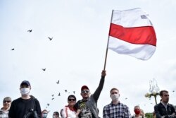 Мітингувальник махає старим білоруським прапором у Мінську під час збору підписів