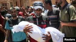 Un bărbat poartă un cadavru lângă spitalul Nasser, după raidul israelian care a lovit o tabără de corturi, în Khan Younis, în sudul Fâșiei Gaza, 13 iulie 2024. REUTERS/Hatem Khaled