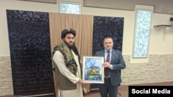 یکی از اعضای هیأت طالبان یک نقاشی از مدیر اجرایی شرکت بلاروسی BelAZ را که متخصص در ماشین‌آلات است دریافت می‌کند.