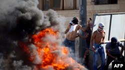 Демонстранты в масках бросают камни в израильских полицейских. Восточная часть Иерусалима, 2 июля 2014 года.