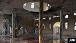 تمیز کردن کف مسجد آخوروال پس از بمب‌گذاری انتحاری، ۵ نوامبر ۲۰۱۰.