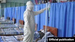 Медик в защитном костюме рядо с пациентом в одном из временных стационаров в Бишкеке. Июль 2020 года. 