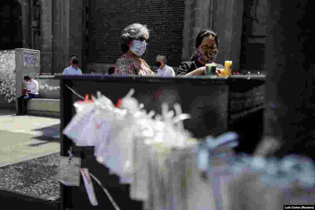 A mexikói Guadalupe bazilikájánál a COVID-ban elhunytak halotti értesítői mellett gyújtanak mécsest a hozzátartozók szeretteik emlékére.