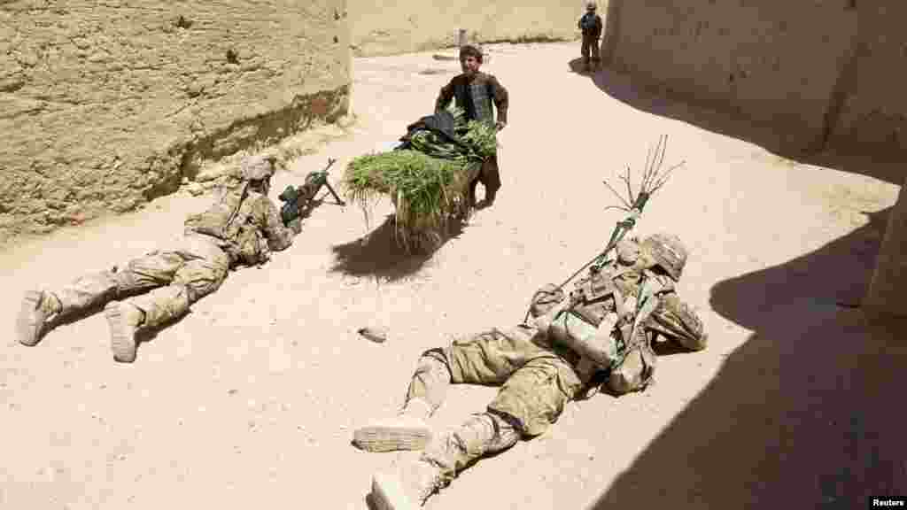 A boy pushes a wheelbarrow next to U.S. Army soldiers securing an area during a joint patrol with Afghan forces in the town of Senjaray in Kandahar Province on May 23. (Reuters/Shamil Zhumatov)