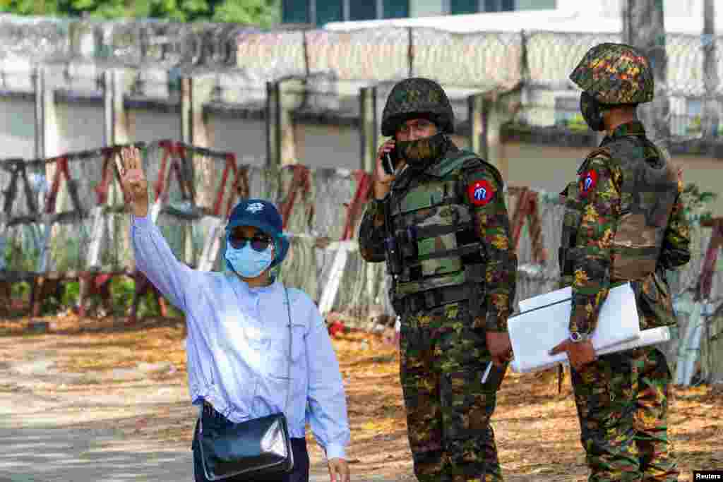 Жінка махає рукою, стоячи поруч із солдатами біля будівлі Центрального банку М&#39;янми під час акції протесту проти військового перевороту. Янгон, М&#39;янма, 15 лютого 2021 року