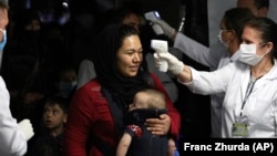 Health workers check the temperature of evacuated citizens from Afghanistan upon their arrival at Tirana International Airport in Albania in August 2021.