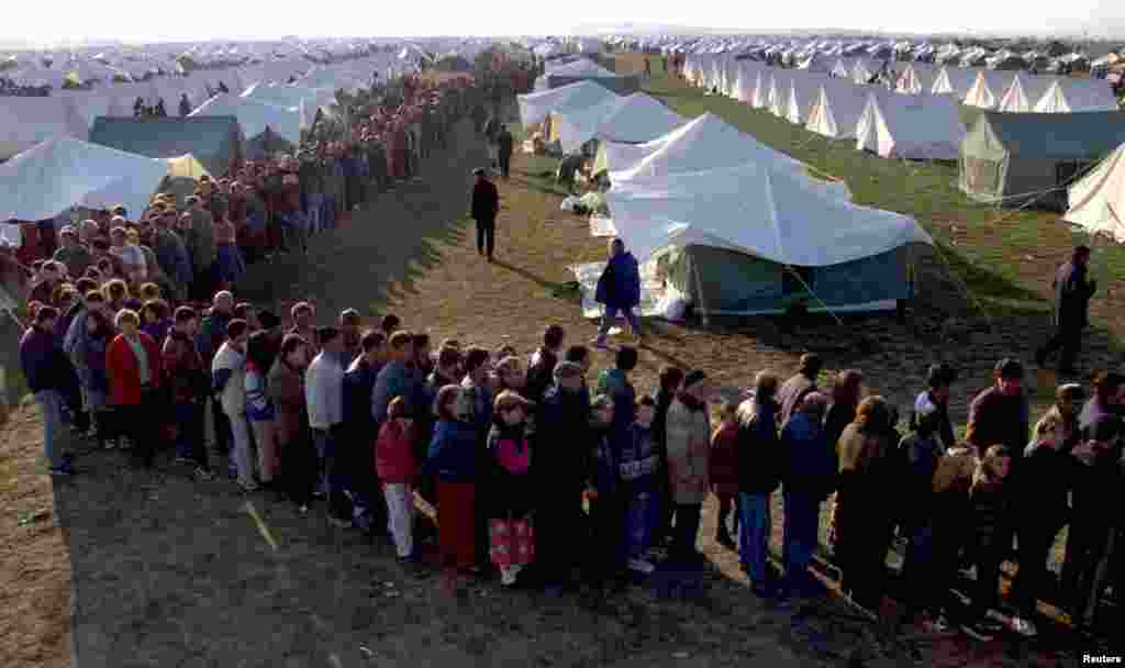 Qindra refugjatë shqiptarë presin për të marrë ushqime në një kamp refugjatësh në afërsi të Shkupit, 8 prill&nbsp;1999. David Silverman/Reuters.&nbsp; 