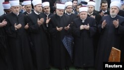 The grand mufti of Bosnian Muslims, Mustafa Ceric (right), and others pray at the grave of General Rasim Delic in Sarajevo.