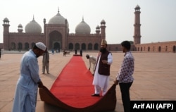 Workers roll out a red carpet at the Badshahi Mosque in Lahore, ahead of the royal visit to the historic site on October 17.