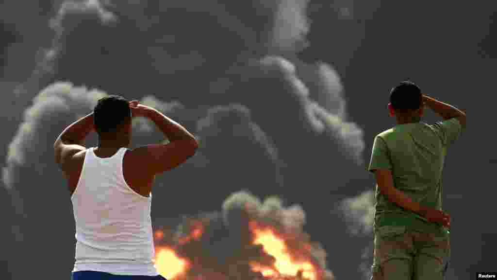 Venezuelans watch fuel storage tanks burn at the Amuay oil refinery in Punto Fijo in the Peninsula of Paraguana. (REUTERS/Stringer)