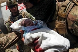 An Afghan soldier carries an injured baby from the hospital after the attack in Kabul on May 12.