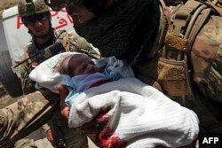 An Afghan soldier carries an injured baby from the hospital after the attack in Kabul on May 12.