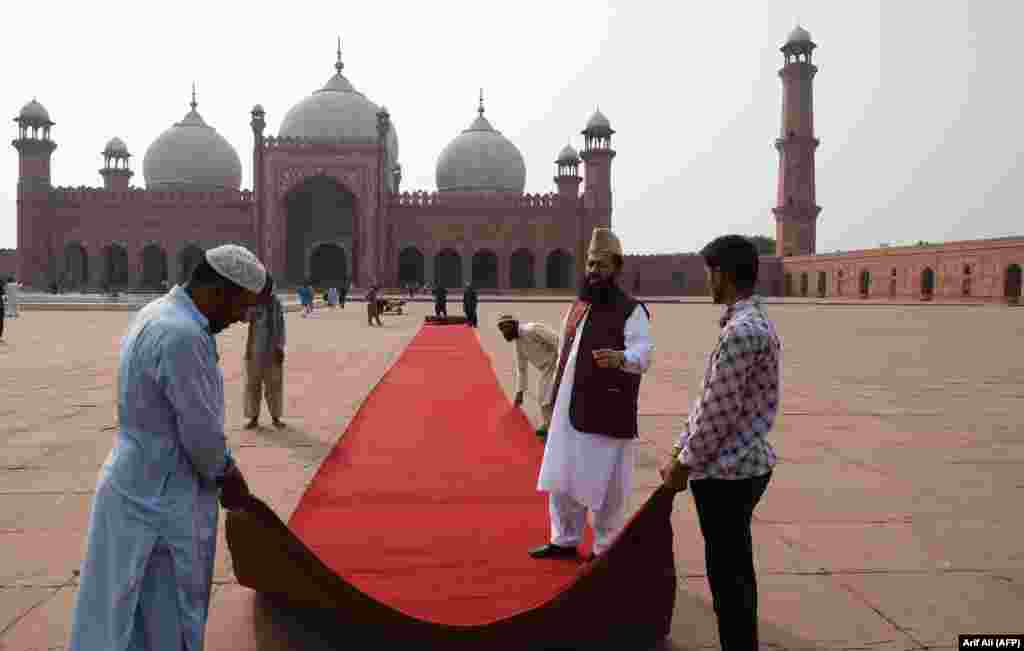 Workers roll out a red carpet at the Badshahi Mosque in Lahore, ahead of the royal visit to the historic site on October 17.