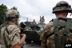 Яворівський полігон. Українські солдати спостерігають за американськими військовослужбовцями, які в свою чергу вивчають український бронетранспортер