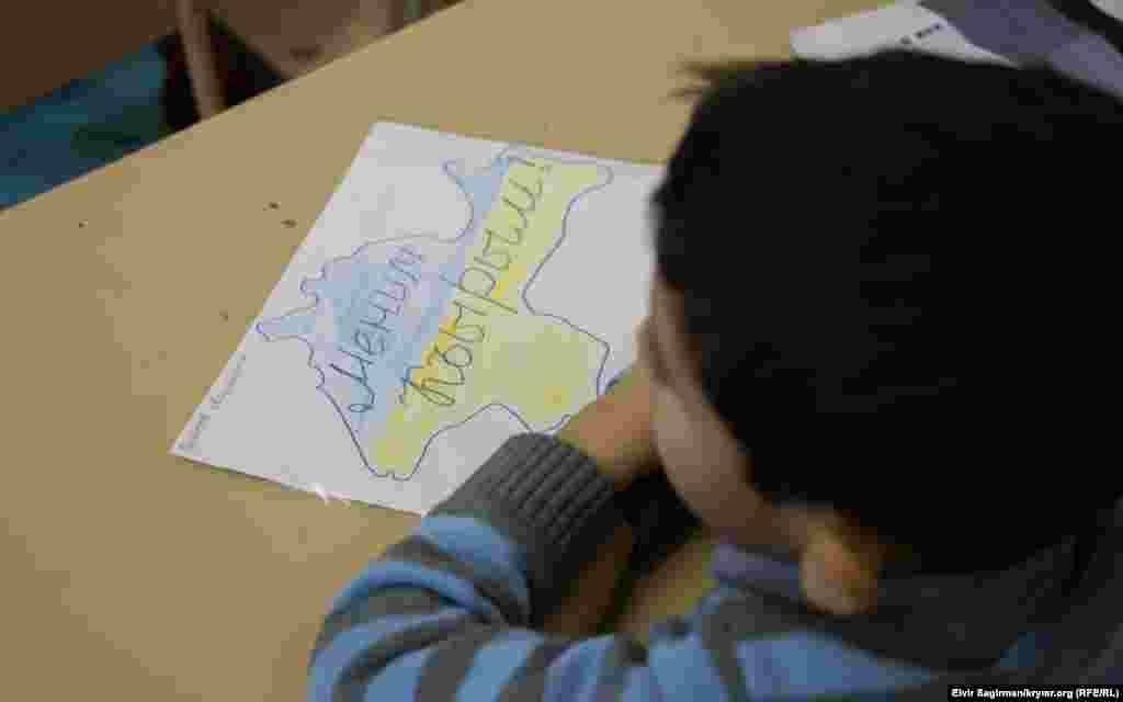Мальчик сидит перед рисунком с подписью &quot;Мой Крым&quot;.