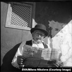 A man reading the Zora (Morning) newspaper in 1970. In the background is a poster of legendary Bulgarian wrestler Dan Kolov (1892-1940).