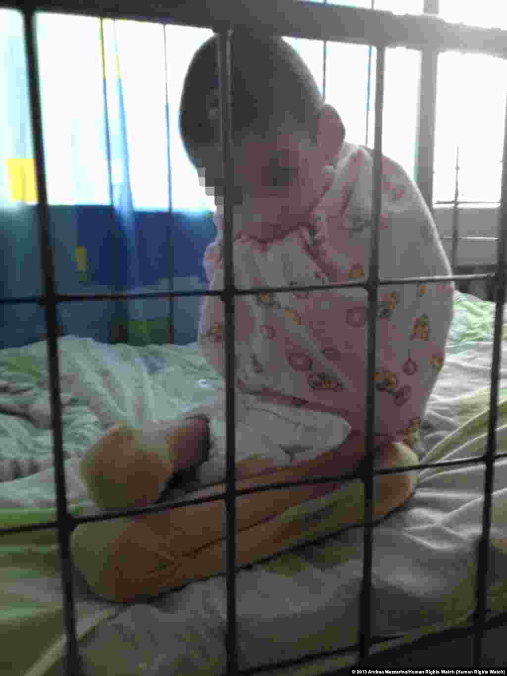 Nikita P., a 10-year-old boy, in his crib in a Sverdlovsk region orphanage for children with developmental disabilities.
