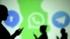 Silhouettes of mobile users are seen next to logos of social media apps Signal, Whatsapp and Telegram projected on a screen in this picture illustration taken March 28, 2018.