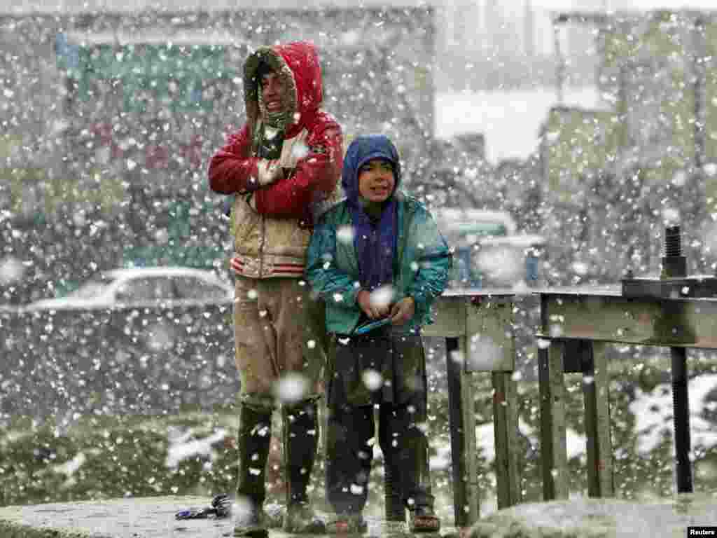 Boys wait for a bus on a roadside amid snowfall in the Afghan capital, Kabul, on March 2. Photo by Ahmad Masood for Reuters