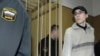 Roman Popkov is escorted into the defendants' cage before a session at a court in Moscow in March 2008.