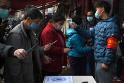 Секьюрити сканирует персональные QR-коды, измеряет температуру и только после этого пропускает людей на рынок, город Куньмин, февраль 2020 года