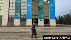 Қазақстан Конституциясын өзгерту жөніндегі референдум жарнамасы ілінген ғимараттың  қасынан өтіп бара жатқан адам. Орал, 11 наурыз, 2026 жыл.