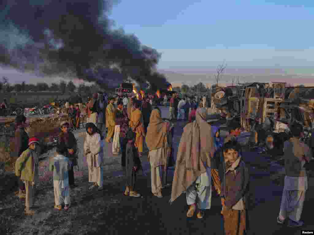 Pakistan residents stand near fuel trucks that were set ablaze in the Bolan district of Balochistan Province in December.