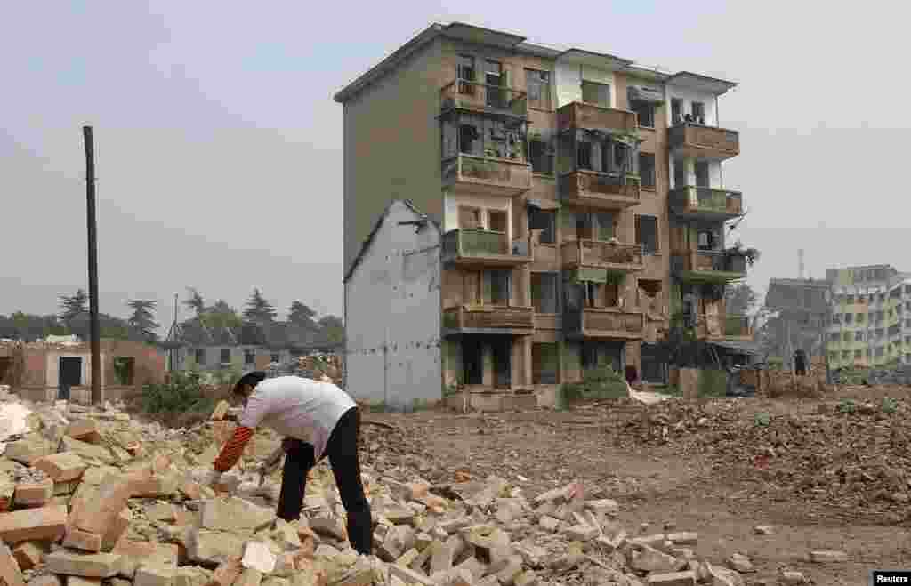 Градежен работник собира цигли околу &bdquo;клинец&ldquo; куќа во центарот градилиштето за нов блок станбени згради во Хефеи, источна кинеска провинција Анхуи. Фотографирано на 5 ноември, 2007 година. &nbsp;