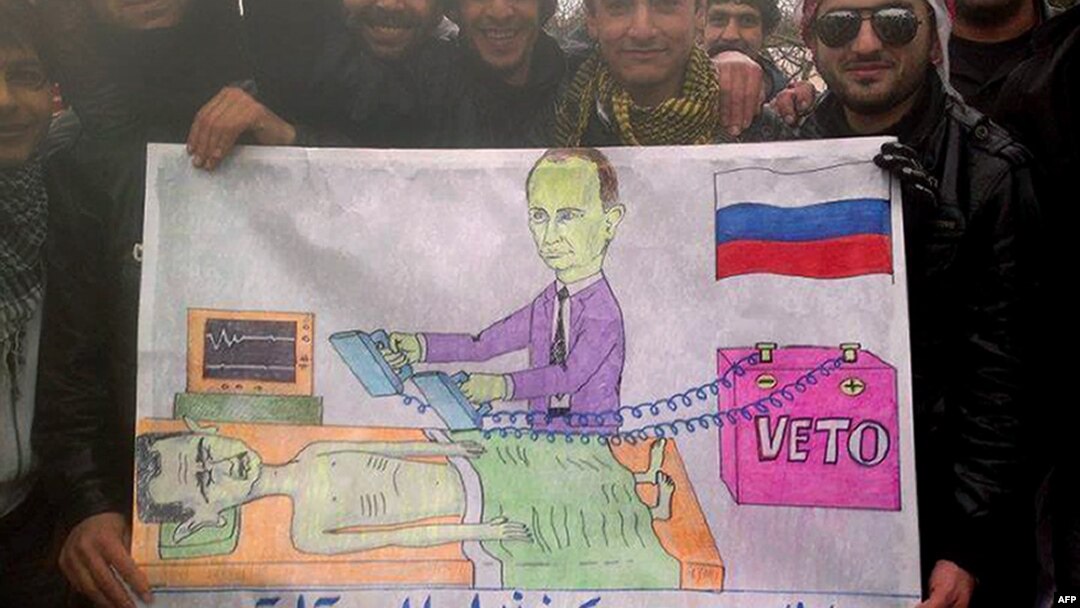 Syrians in the northwestern town of Kfar Nubul pose with a cartoon depicting Russia's Vladimir Putin defibrillating Syrian President Bashar al-Assad by using a veto to block a UN resolution against Assad.