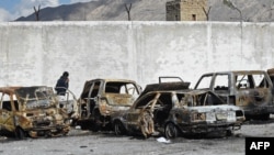 A man walks past burned vehicles in a torched police station on the outskirts of Quetta on February 1, a day after an attack by Baluch separatists.