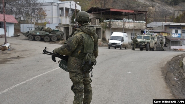 A Russian peacekeeper stands guard on a road in the town of Lachin on December 1, 2020.