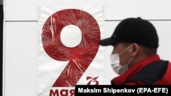 Чоловік у захисній масці на тлі агітаційного плакату з нагоди 75-ї річниці завершення Другої світової війни в Європі, Москва, 5 травня 2020 року