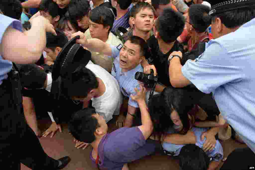 People fall during a stampede to see British football superstar David Beckham at Tonji University in Shanghai, where he was to meet members of the university's soccer team. At least seven people were injured in the melee, including a policewoman, as about 1,000 fans rushed forward. The event was subsequently canceled. (AFP/Peter Parks)