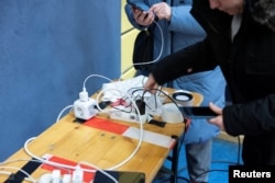 Люди заряджають телефони в аварійному пункті, організованому у спортзалі, Берлін, 4 січня 2026 ркоу