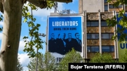Një pllakat i madh, i vendosur në qendër të Prishtinës, që bën thirrje për lirimin e ish-eprorëve të Ushtrisë Çlirimtare të Kosovës.