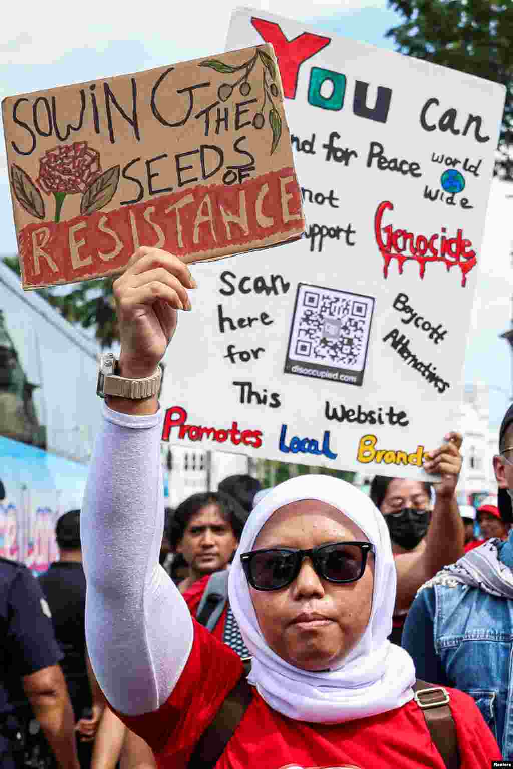 Një protestuese mban një pankartë që bën thirrje për rezistencë dhe paqe gjatë një tubimi për 1 Maj, duke festuar të drejtat e punëtorëve dhe solidaritetin e tyre në Kuala Lumpur, Malajzi.
