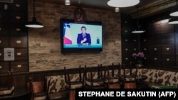 На телеэкране в пустом парижском ресторане президент Франции Эммануэль Макрон.