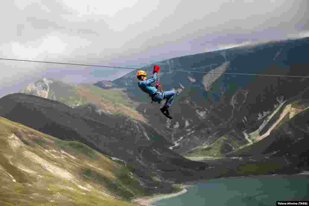 A man rides a zip line on Lake Kezenoyam in the Caucasus Mountains in Russia&#39;s Chechnya region. (TASS/Yelena Afonina)