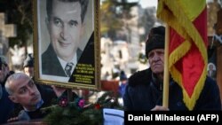 A man holds a portrait of late dictator Nicolae Ceausescu at the tomb of Ceausescu and his wife, Elena, at Ghencea Cemetery in Bucharest on January 26.