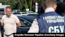 Ukrainian security officer detains a suspect from the anti-corruption office (identity blurred).
