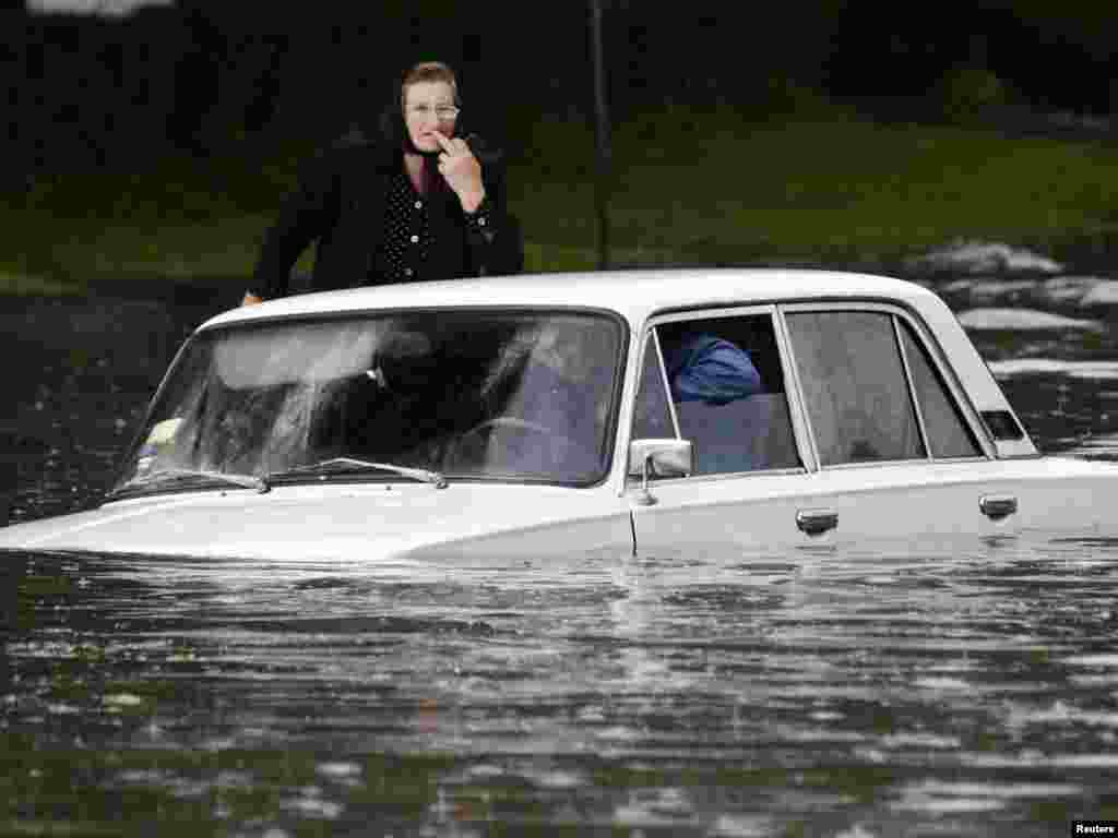 A woman stands by a car stuck in floodwaters in Ternopil, western Ukraine, on June 3 amid severe storms in the region. Photo by Viktor Gurniak for Reuters