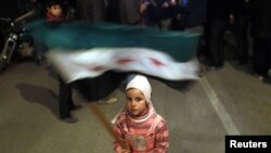 A Syrian girl waves an opposition flag during an antigovernment protest in Al-Qusayr on February 27.