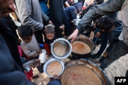 Refugiați palestinieni așteptând mâncare la Rafah, în sudul Fâșiei Gaza, în prima zi a Ramadanului, 11 martie 2024.