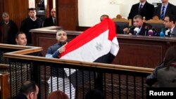 Мухаммед Фахми сот төрагасы менен сүйлөшүп жатканда Египеттин желегин көрсөтүүдө. 12-февраль 2015