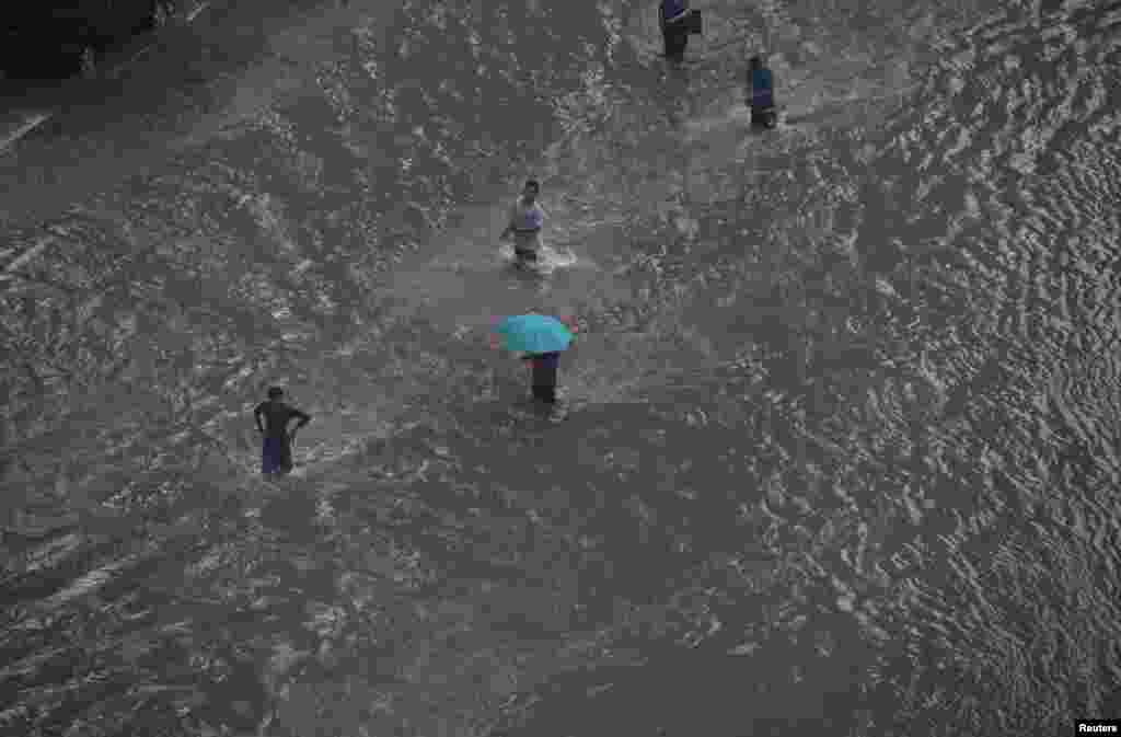 People walk on a flooded street in the business district of Jakarta, Indonesia. Heavy monsoon rains triggered severe flooding in large swathes of the Indonesian capital. (Reuters/Beawiharta)