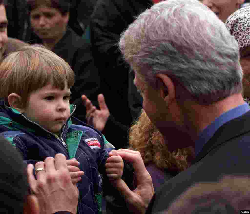 Presidenti amerikan Bill Clinton duke përshëndetur një fëmijë nga Kosova, i cili ka ikur nga lufta dhe është strehuar në Gjermani, 6 maj 1999. Foto Reuters.&nbsp; 