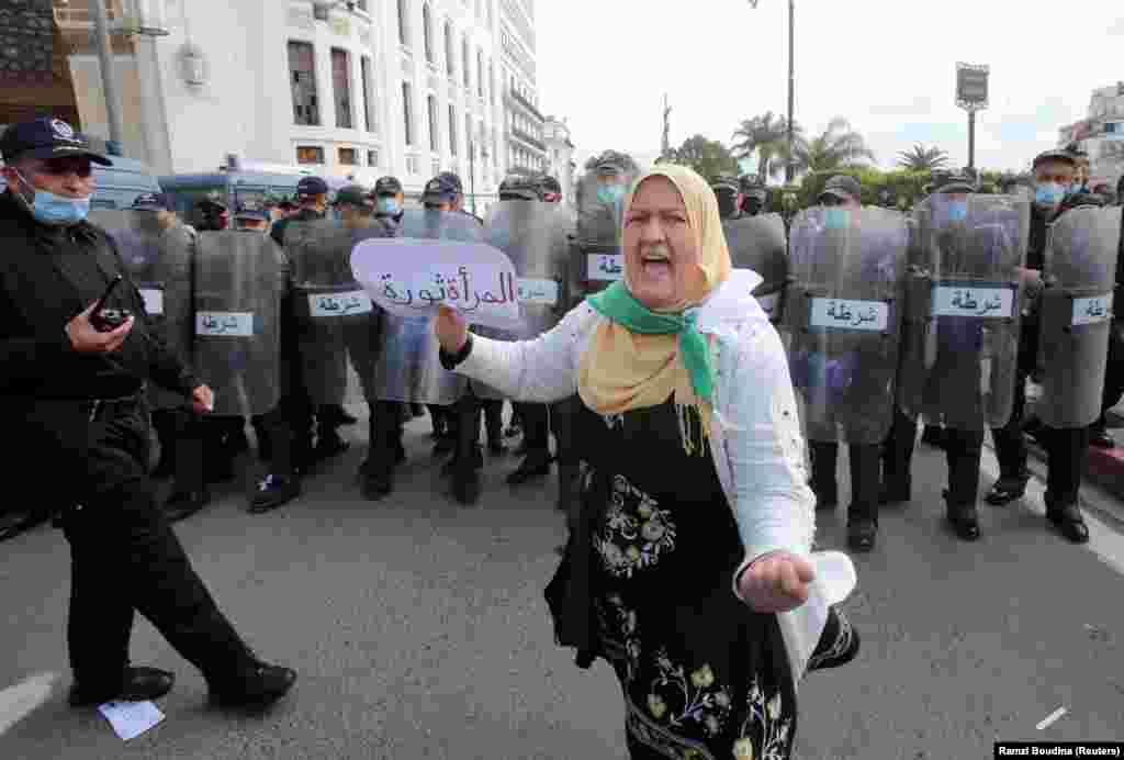 Demonstracije povodom Osmog marta u Alžiru. Žena protestuje ispred policije sa znakom na kojem piše &quot;Žena je revolucija&quot;.&nbsp;